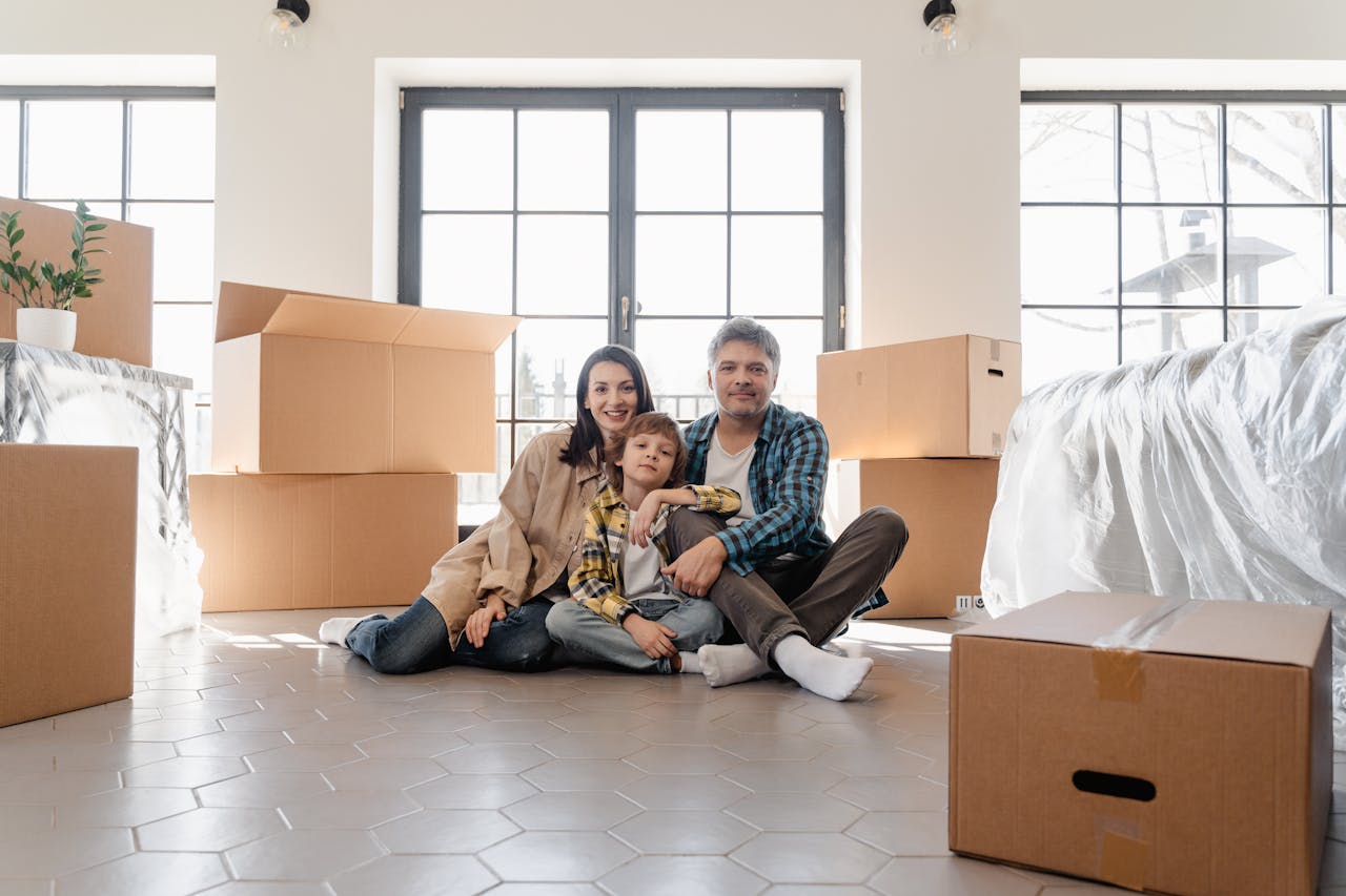 Home A joyful family sitting together amidst moving boxes, marking a new beginning in their home.